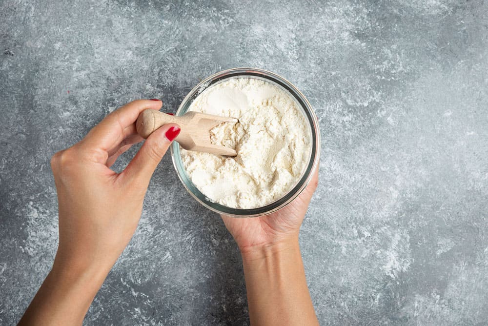 woman-hand-holding-spoon-inside-flour-bowl